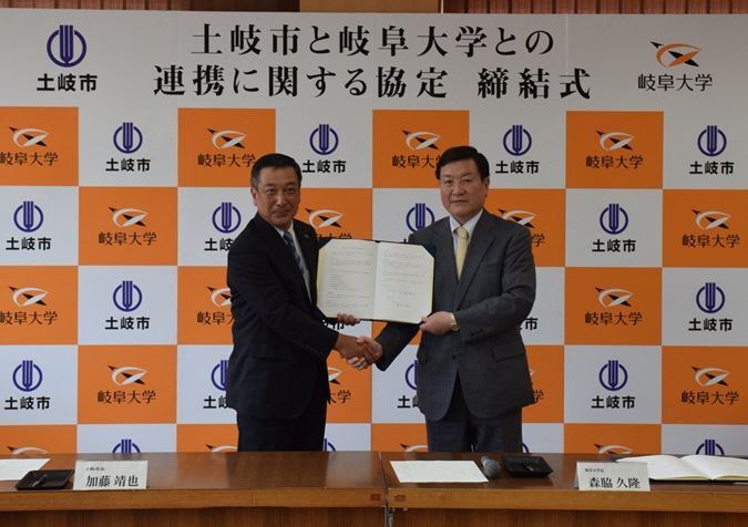 写真：協定書を手に握手を交わす加藤土岐市長と森脇岐阜大学学長